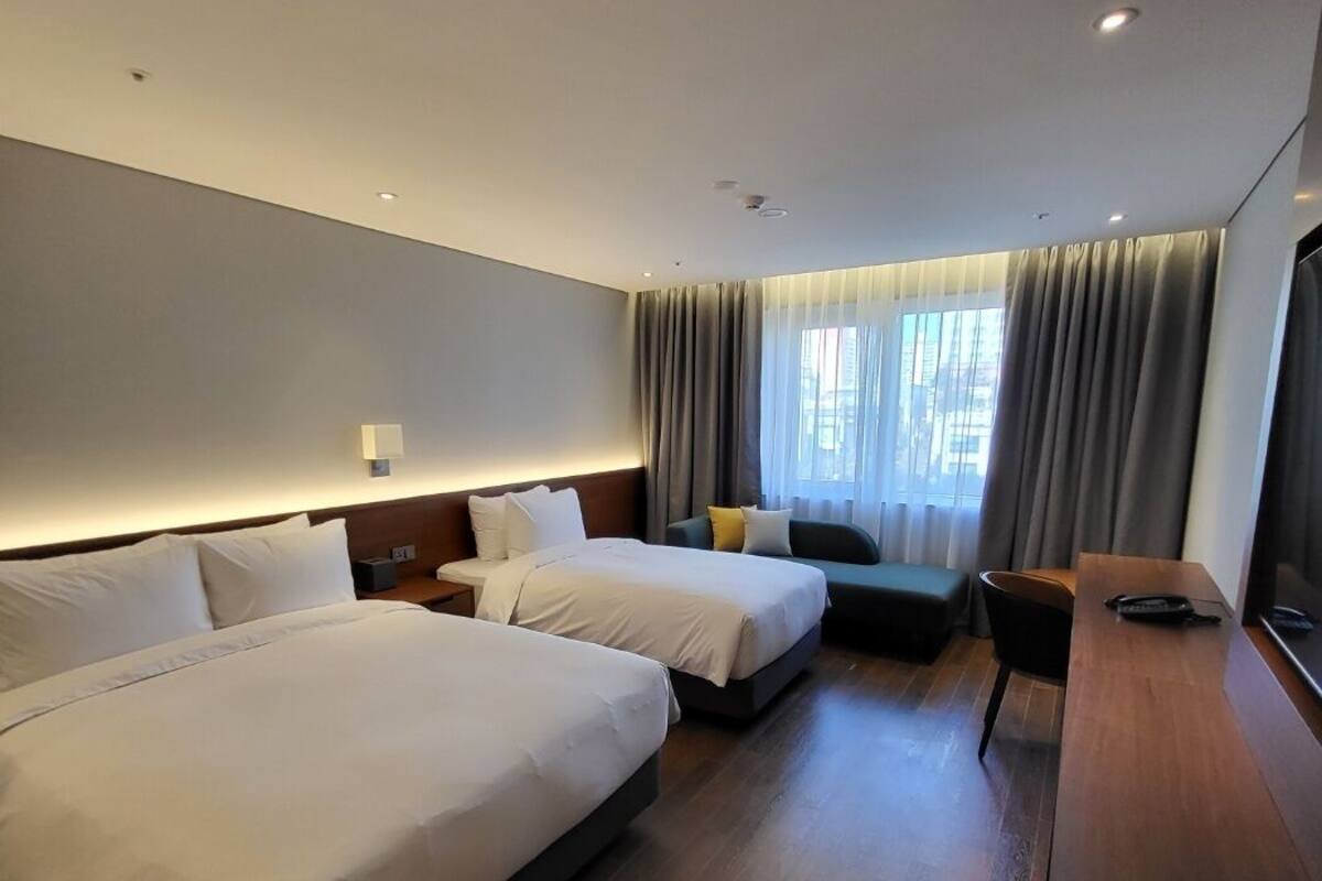 Une chambre d’hôtel moderne avec deux lits, un bureau et une vue sur la ville.