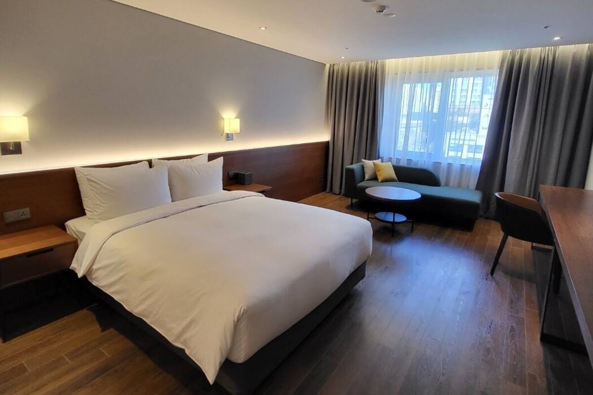 Une chambre d’hôtel moderne avec un grand lit, un canapé, une petite table et un bureau.