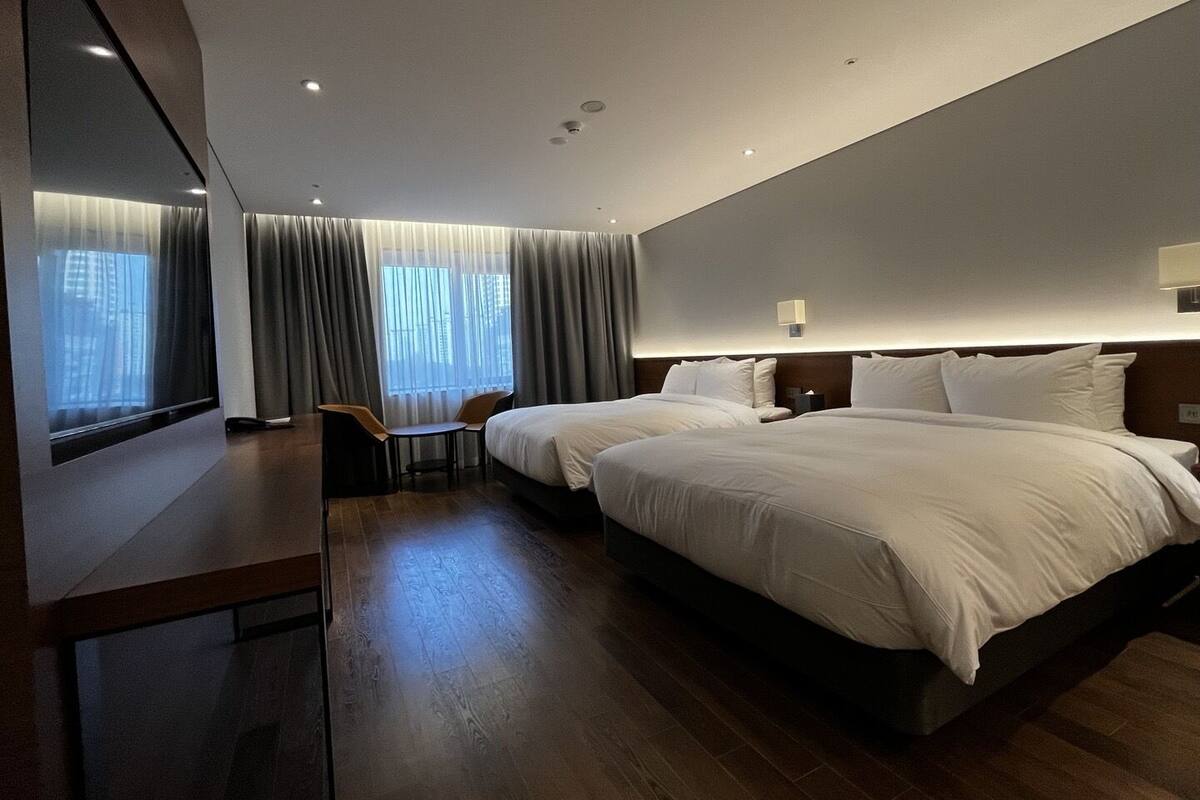 Une chambre d’hôtel moderne avec deux lits, un bureau et une chaise.