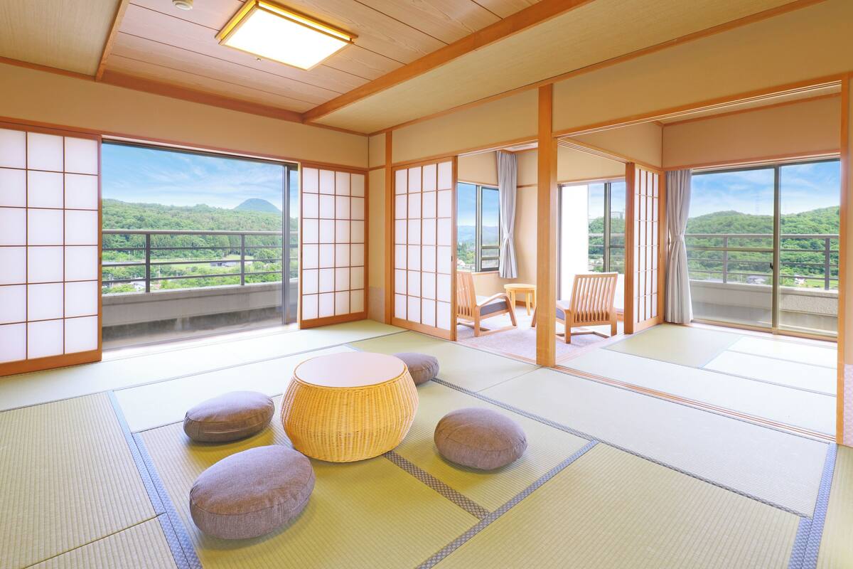 Une pièce de style japonais traditionnel, avec un sol recouvert de tatamis, une table basse, des coussins et des portes coulissantes.