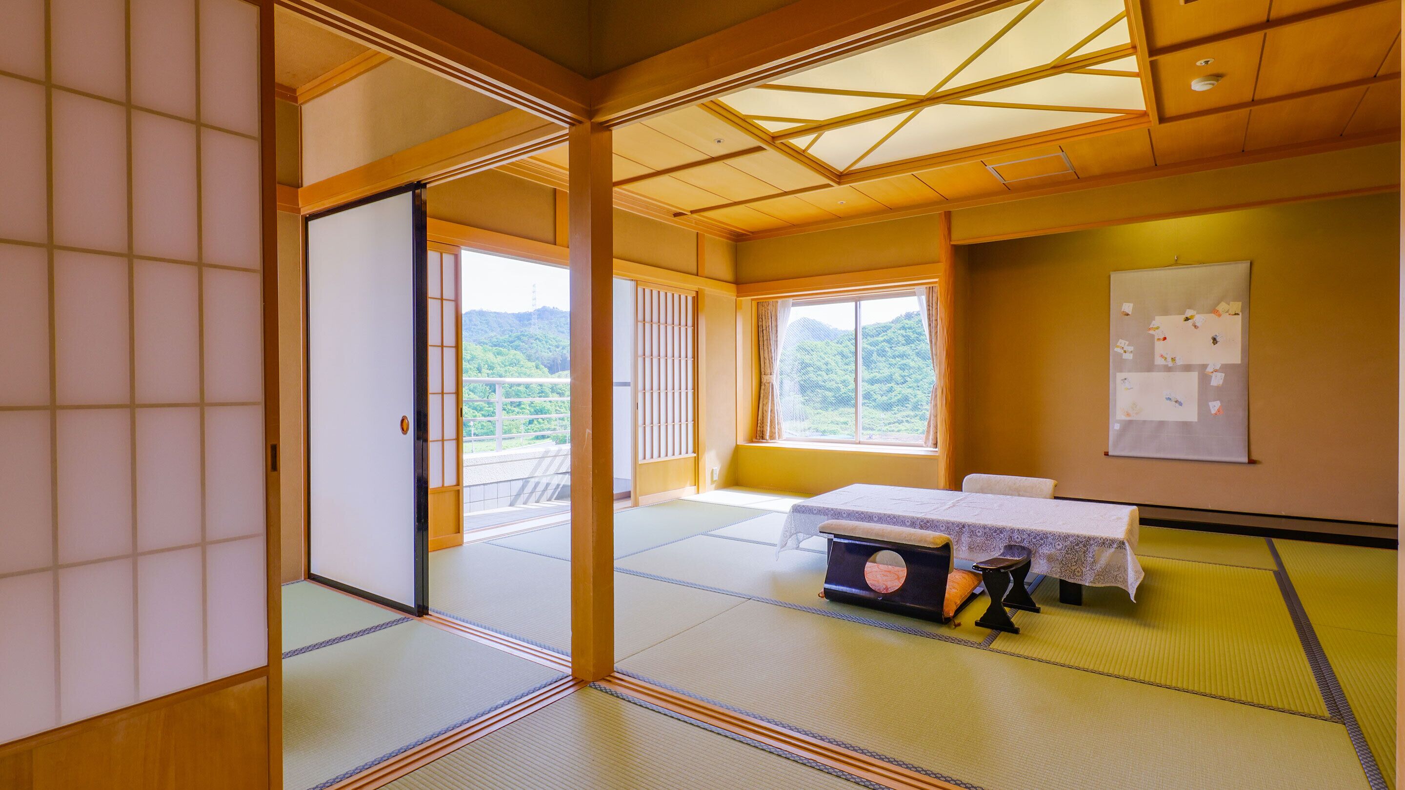 A traditional Japanese room with tatami flooring, a sliding door, a table with a cushion, and a view of greenery outside.