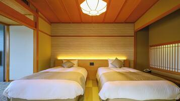 Une chambre d’hôtel avec deux lits, des lambris en bois, un luminaire de plafond de style japonais traditionnel et un téléphone sur la table de chevet.