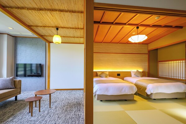 A hotel room with a sofa, a TV, a small table, and two beds with a traditional Japanese aesthetic.
