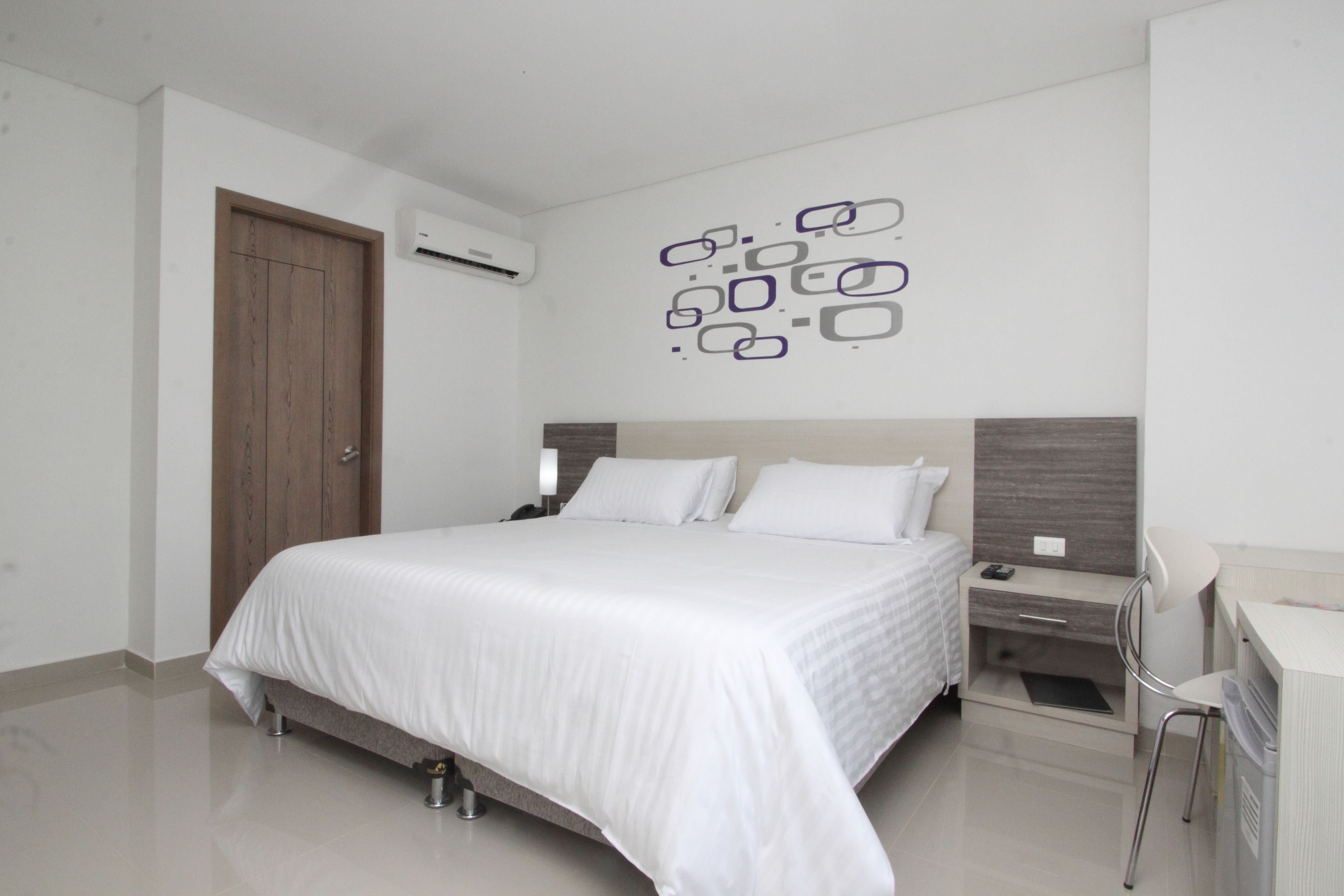 Un dormitorio moderno con una cama grande, mesitas de noche, un escritorio y una silla.