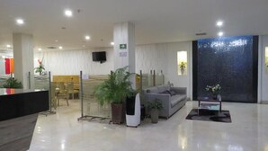 Eine moderne Lobby mit Empfangstresen, einer Sitzgelegenheit und einer großen Wanddekoration.