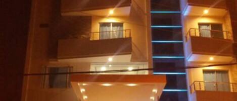 A multi-story hotel with a prominent entrance, a staircase leading to the entrance, and a sign above the entrance.