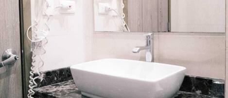 Ein Badezimmer mit einem weißen Waschbecken, einem Spiegel und zwei an der Wand befestigten Haartrocknern.