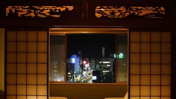 A traditional Japanese room with tatami flooring, a low wooden table, and two cushioned chairs. - Hotel Takasago (Kochi)