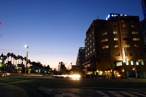 A multi-story hotel with illuminated windows and a blue sign on the top. - Hotel Takasago (Kochi)