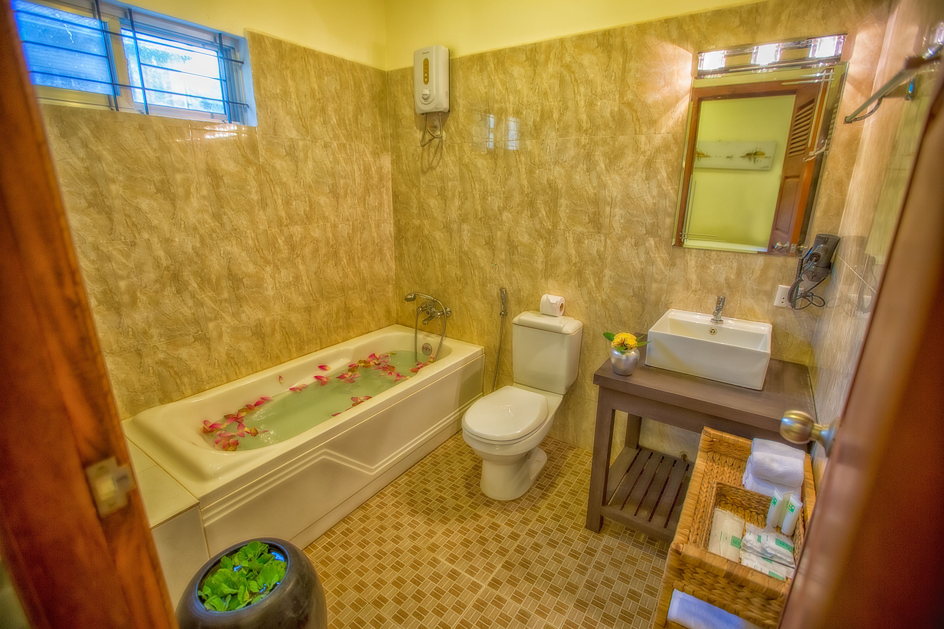 A bathroom with a bathtub, toilet, sink, and a small window.
