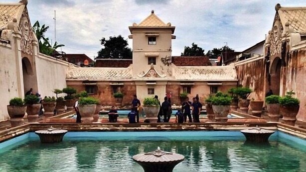 A courtyard with a central pool, surrounded by buildings with ornate architecture and potted plants. - Griya Nendra Hotel (Ngaglik)