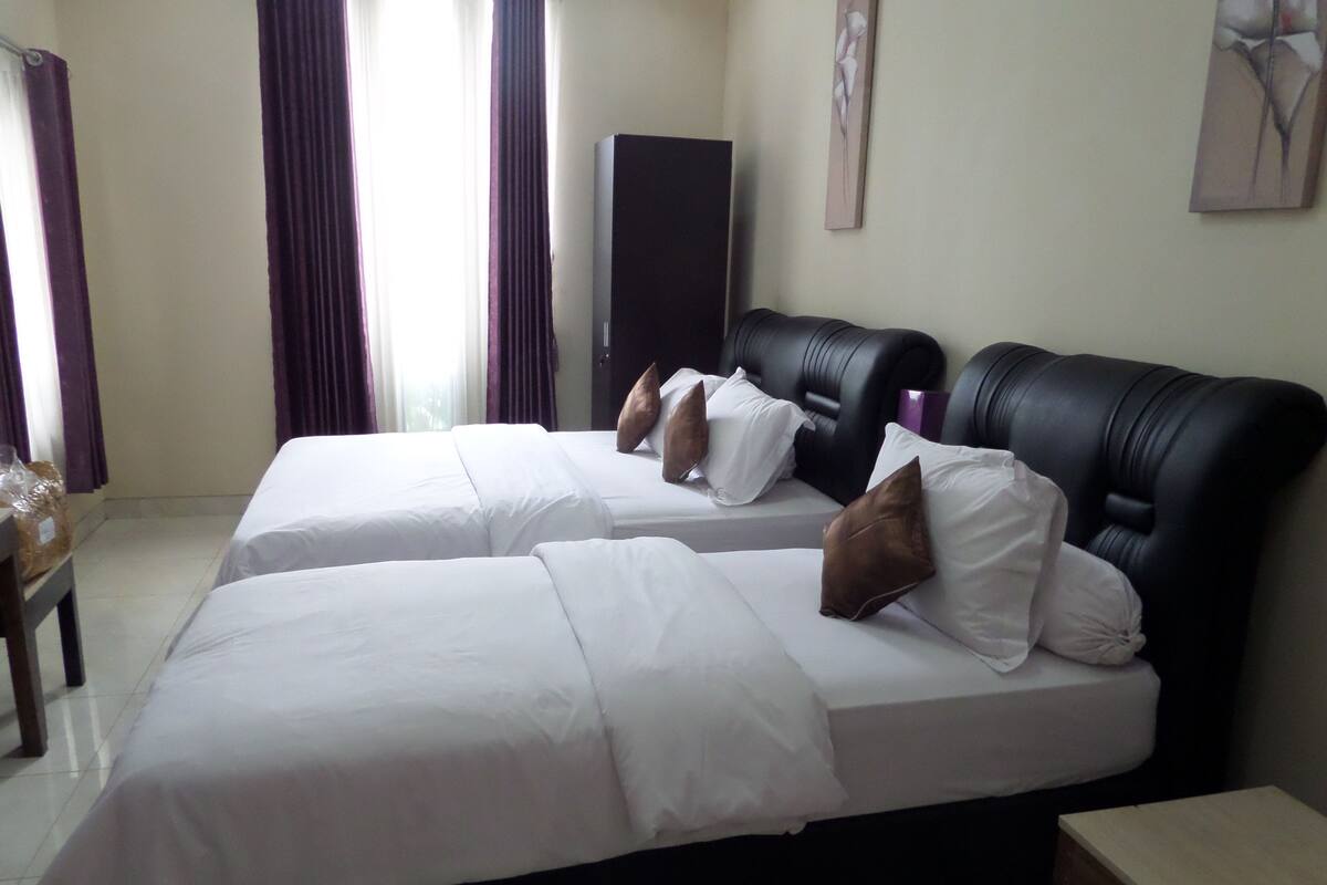 A hotel room with two beds, a small table, and a TV.