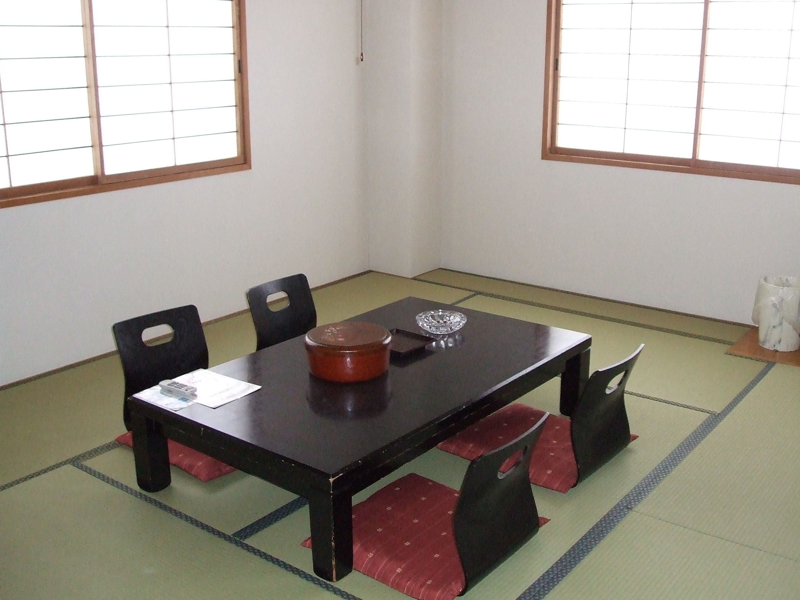 A traditional Japanese tatami room with a low wooden table, black chairs, and a shoji screen.