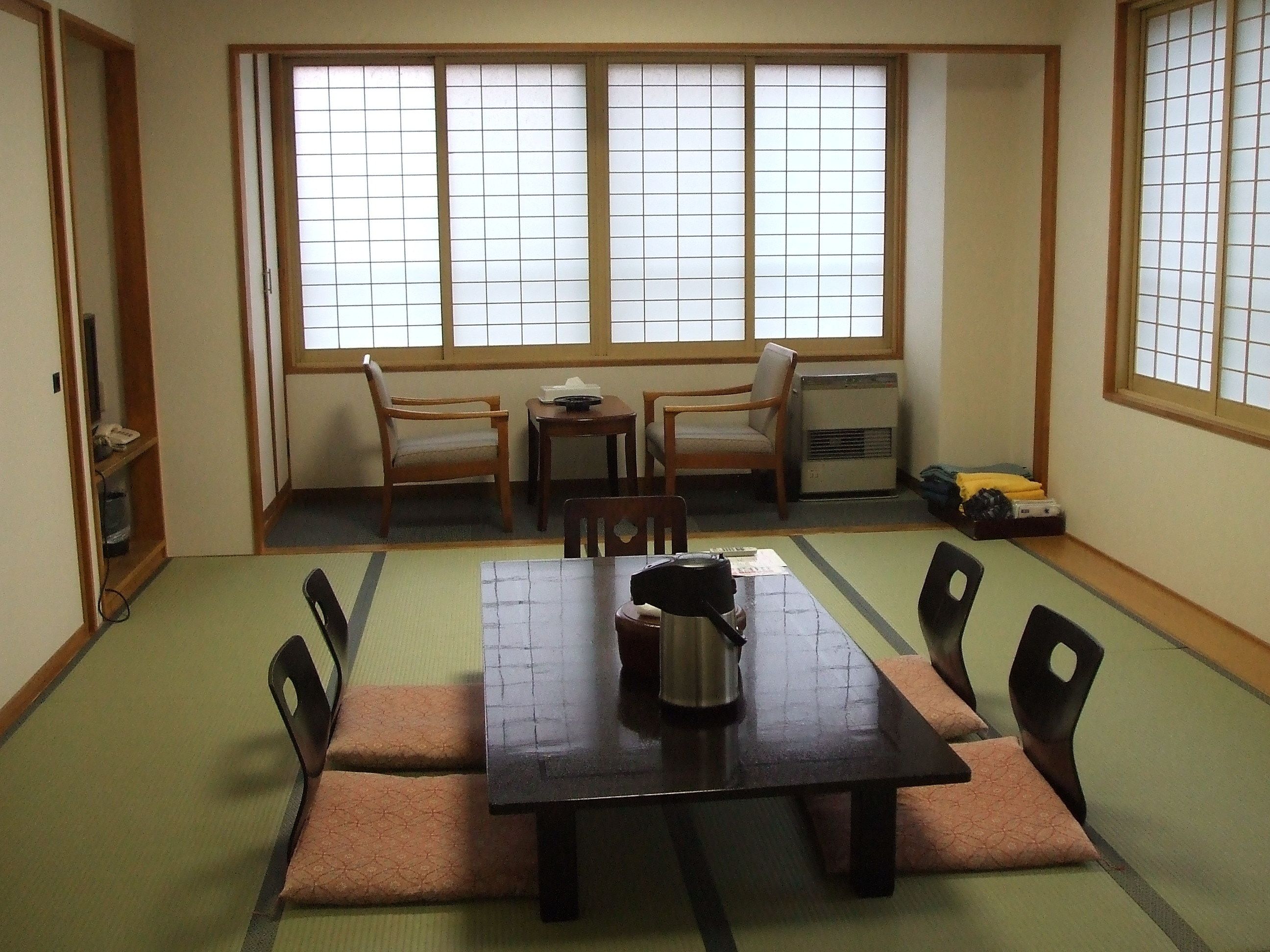 Una habitación tradicional japonesa con suelo de esteras de tatami, una mesa baja con cojines y una puerta corredera.