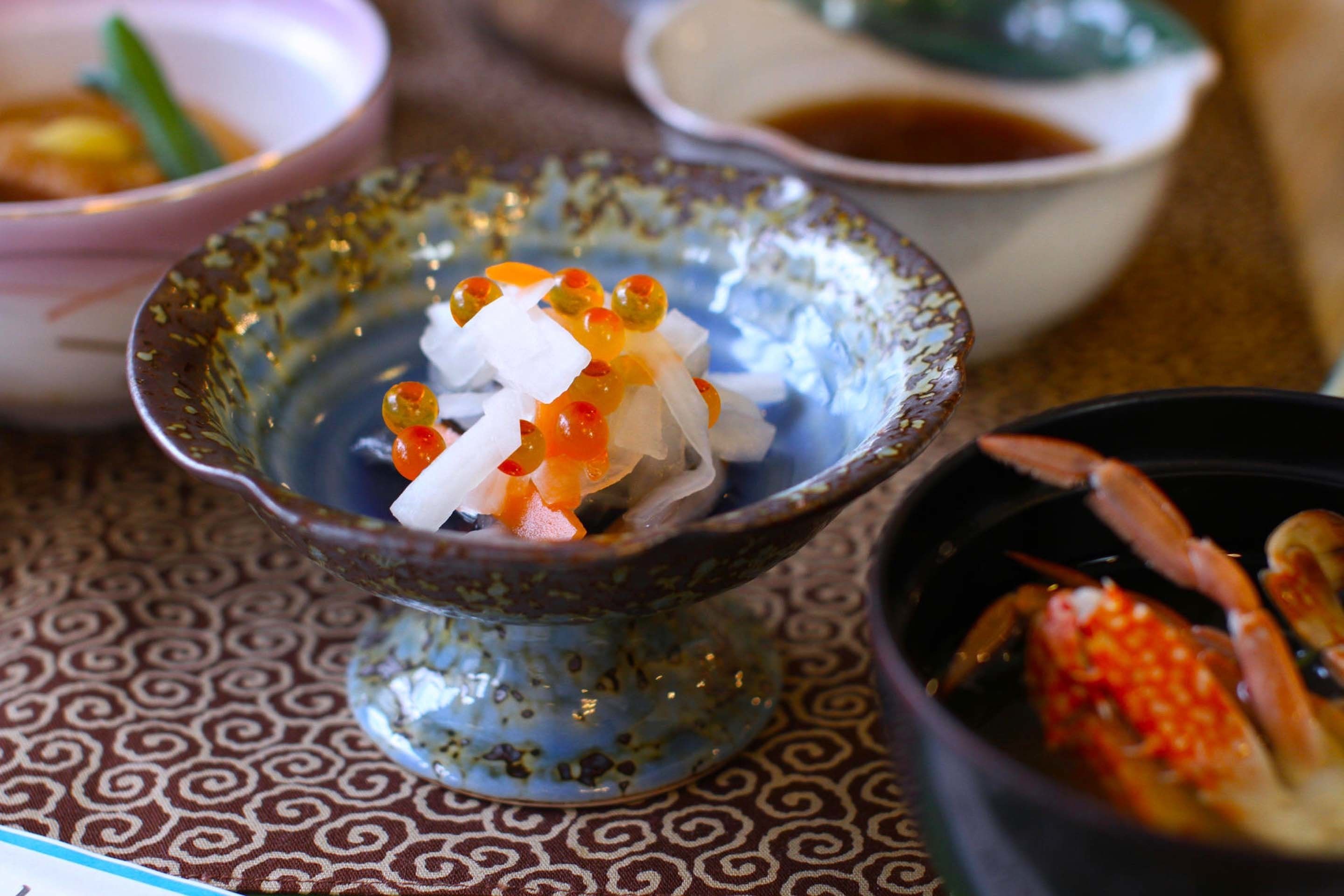 A bowl of rice with toppings, a bowl of soup, and a bowl of crab.