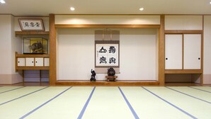 Una habitación con esteras de tatami, un biomblo shoji, un cuadro enmarcado y una pequeña estatua.