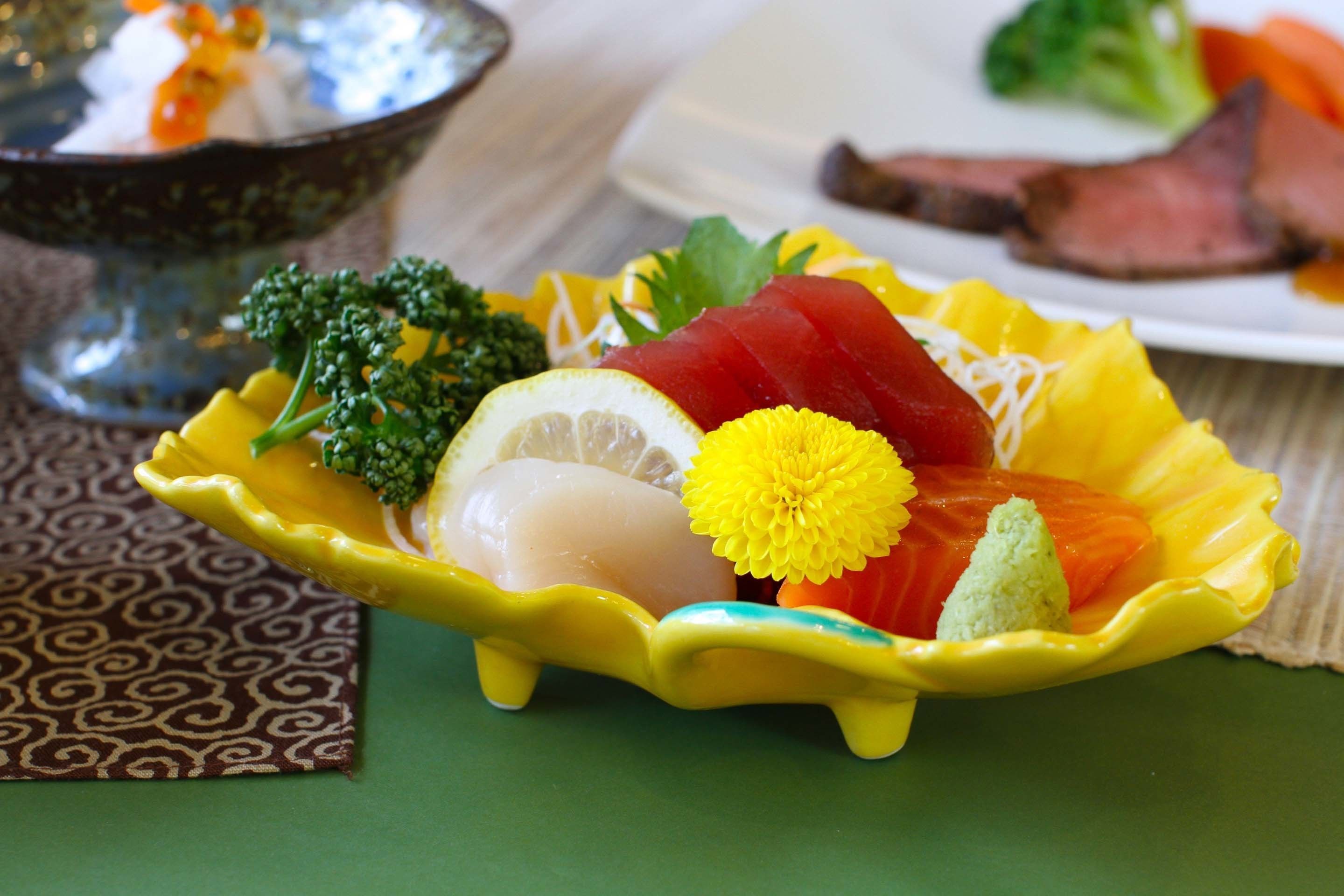 Un plato con distintos alimentos, incluyendo salmón, brócoli y una flor amarilla.