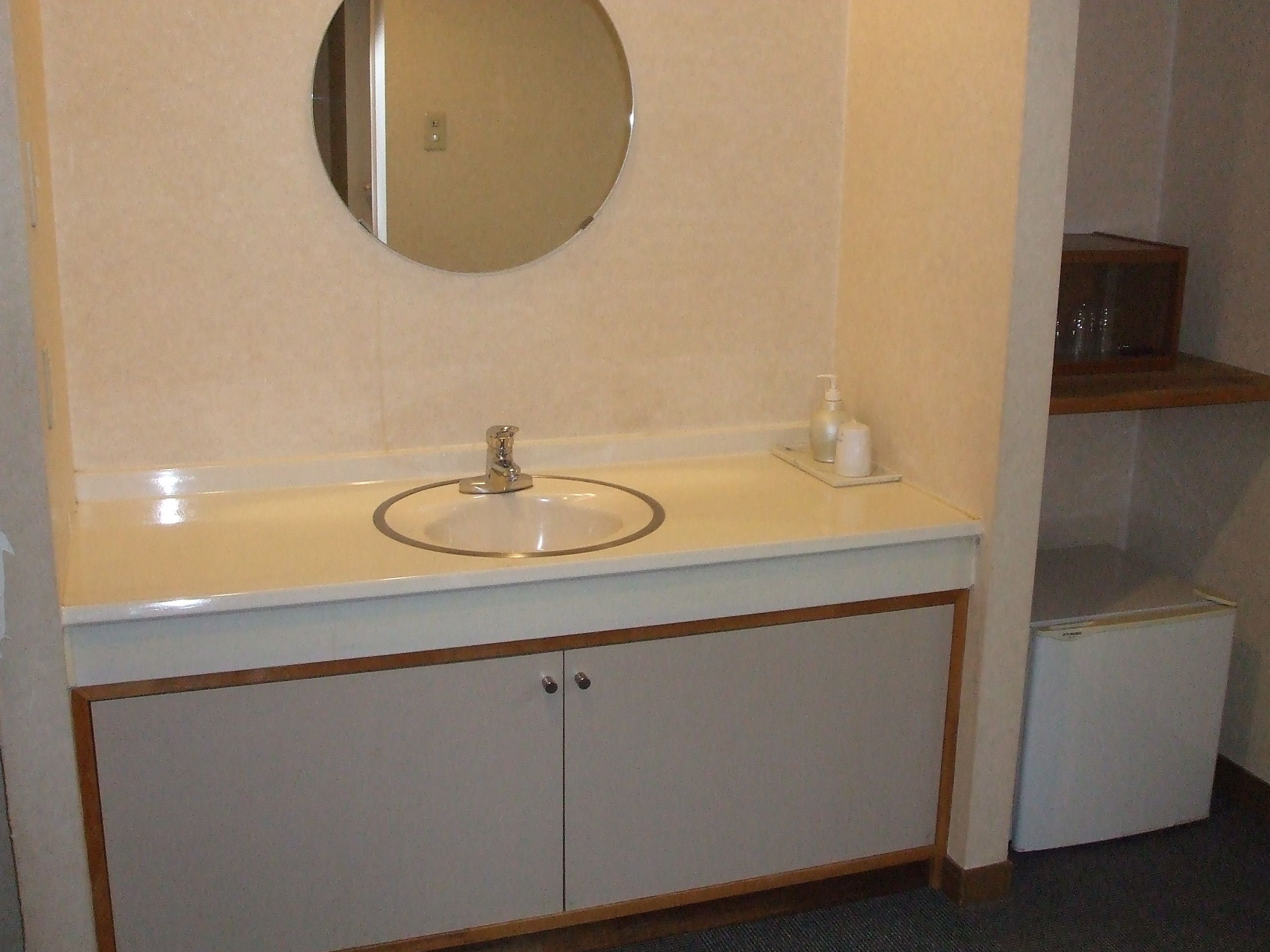 A bathroom with a round mirror, a sink, and a cabinet.