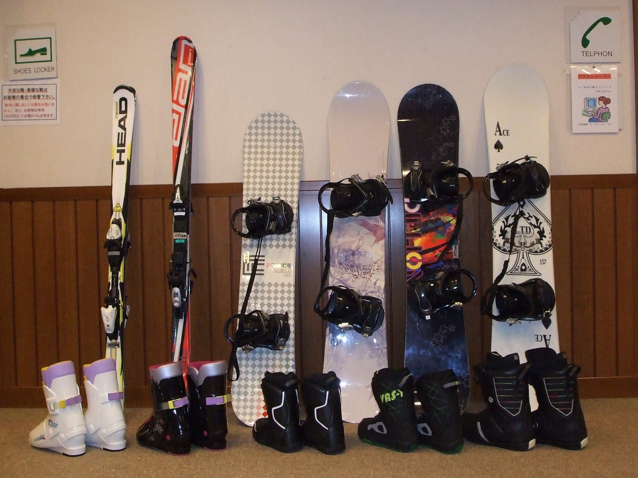 Una pared con diverso equipo de snowboard y un par de esquíes.