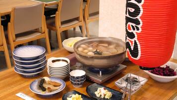 A dining table with various dishes, including a bowl of soup, plates, and bowls of food.