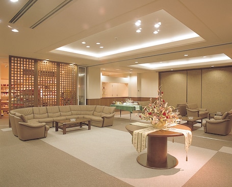 A spacious lobby with a sectional sofa, a round coffee table, and a decorative vase.