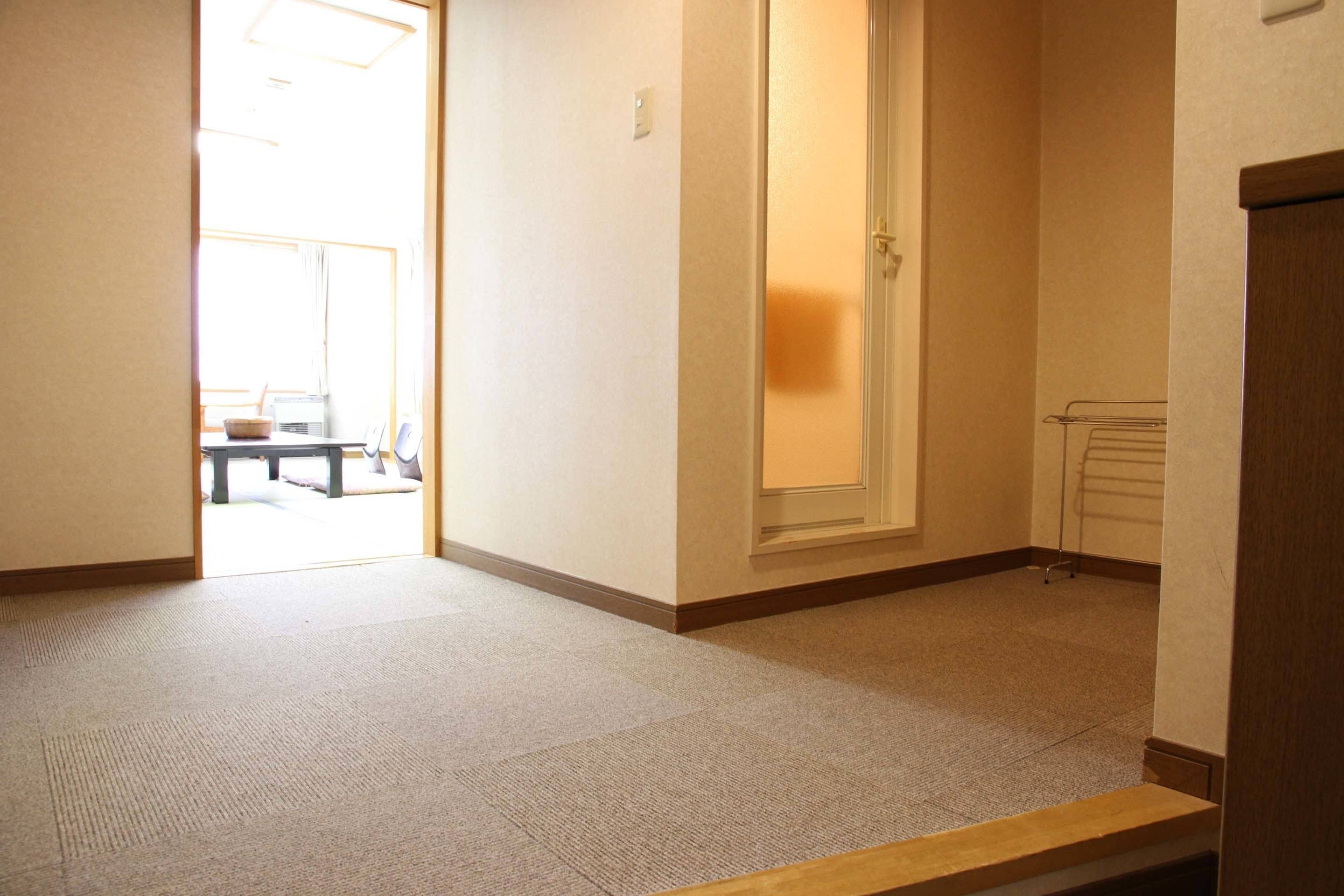 A hallway with carpeted floors, a door, and a small table with a bowl and spoon.