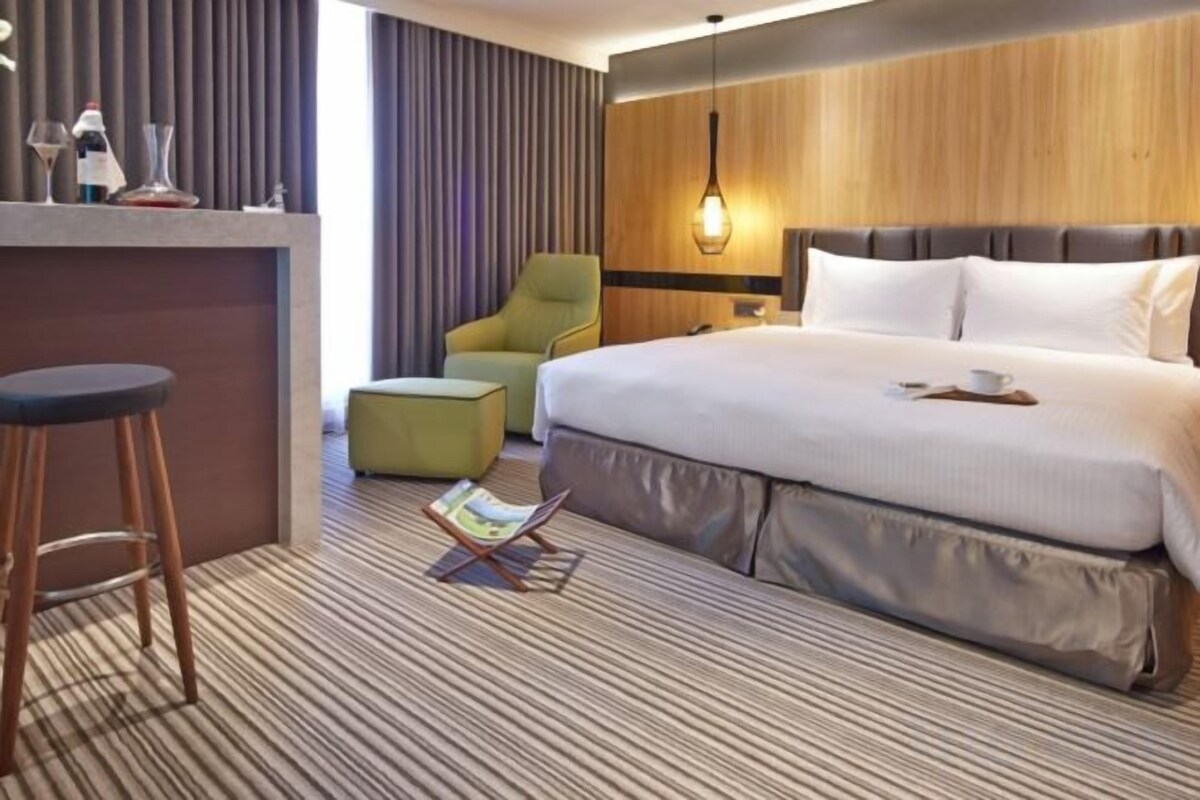 A hotel room with a bed, a desk, a chair, and a reading area.