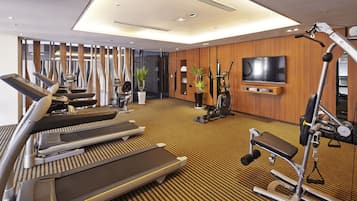 Ett hotells gym med löpband, motionscyklar och en tv på väggen.