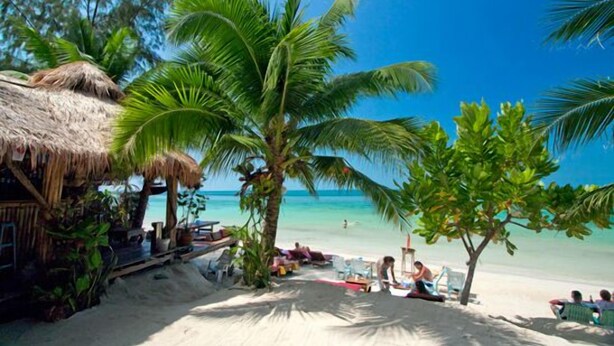 A beach scene with a thatched-roof hut, palm trees, and people relaxing on the sand. - Haad Yao Resort (Ko Pha-ngan)