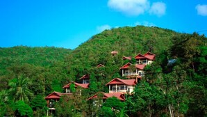 A hillside with multiple red-roofed buildings, likely part of a resort or lodge. - Haad Yao Resort (Ko Pha-ngan)