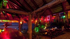 An outdoor dining area with tables and chairs, a thatched roof, and string lights. - Haad Yao Resort (Ko Pha-ngan)