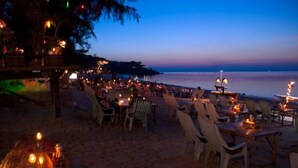 An outdoor seating area with tables and chairs, a beach view, and a calm sea at dusk. - Haad Yao Resort (Ko Pha-ngan)
