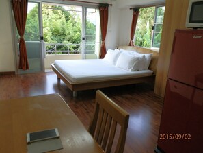 A room with a bed, a table, a chair, and a refrigerator.