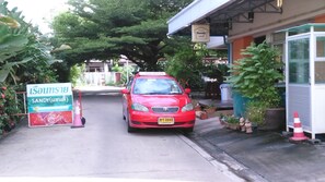 A red car parked in front of a building with a sign that reads "Sandy."