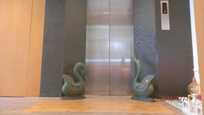 Un ascensor con diseño moderno, flanqueado por dos esculturas decorativas de cisnes.