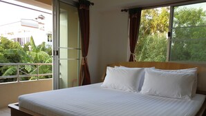 Un dormitorio con una cama, una ventana con cortinas y vistas al verdor exterior.