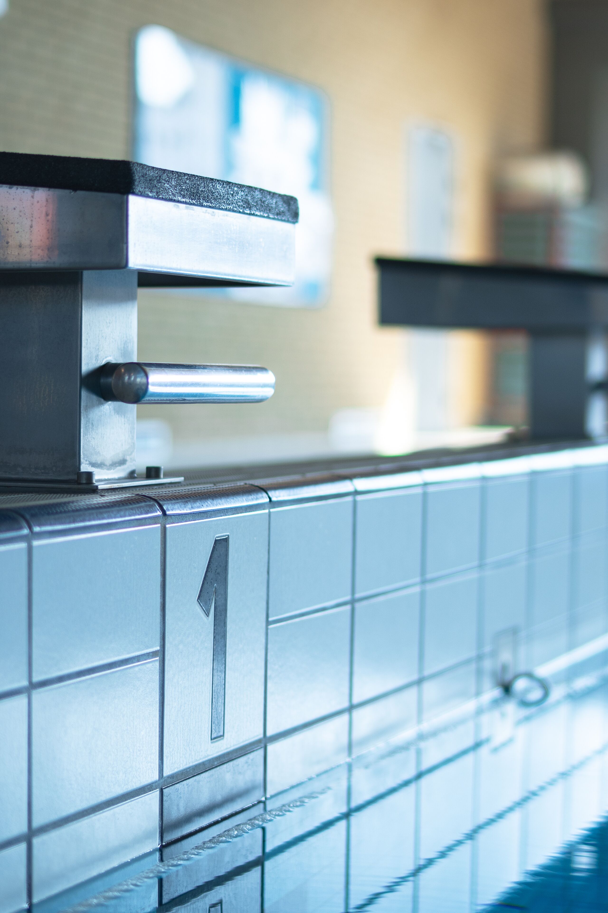 A bathroom with a tiled wall, a metal sink, and a towel rack.