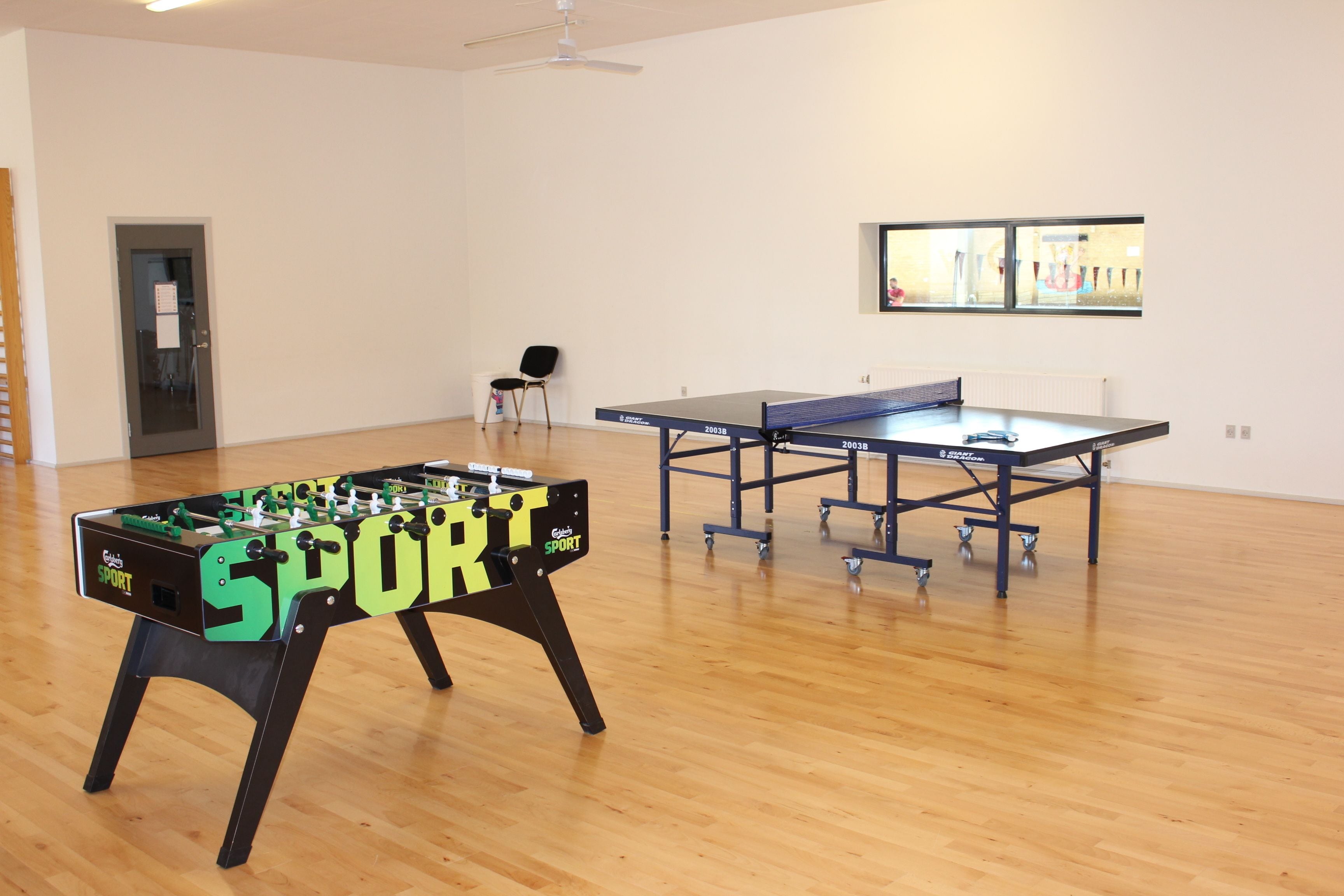 A room with a foosball table and a ping pong table.