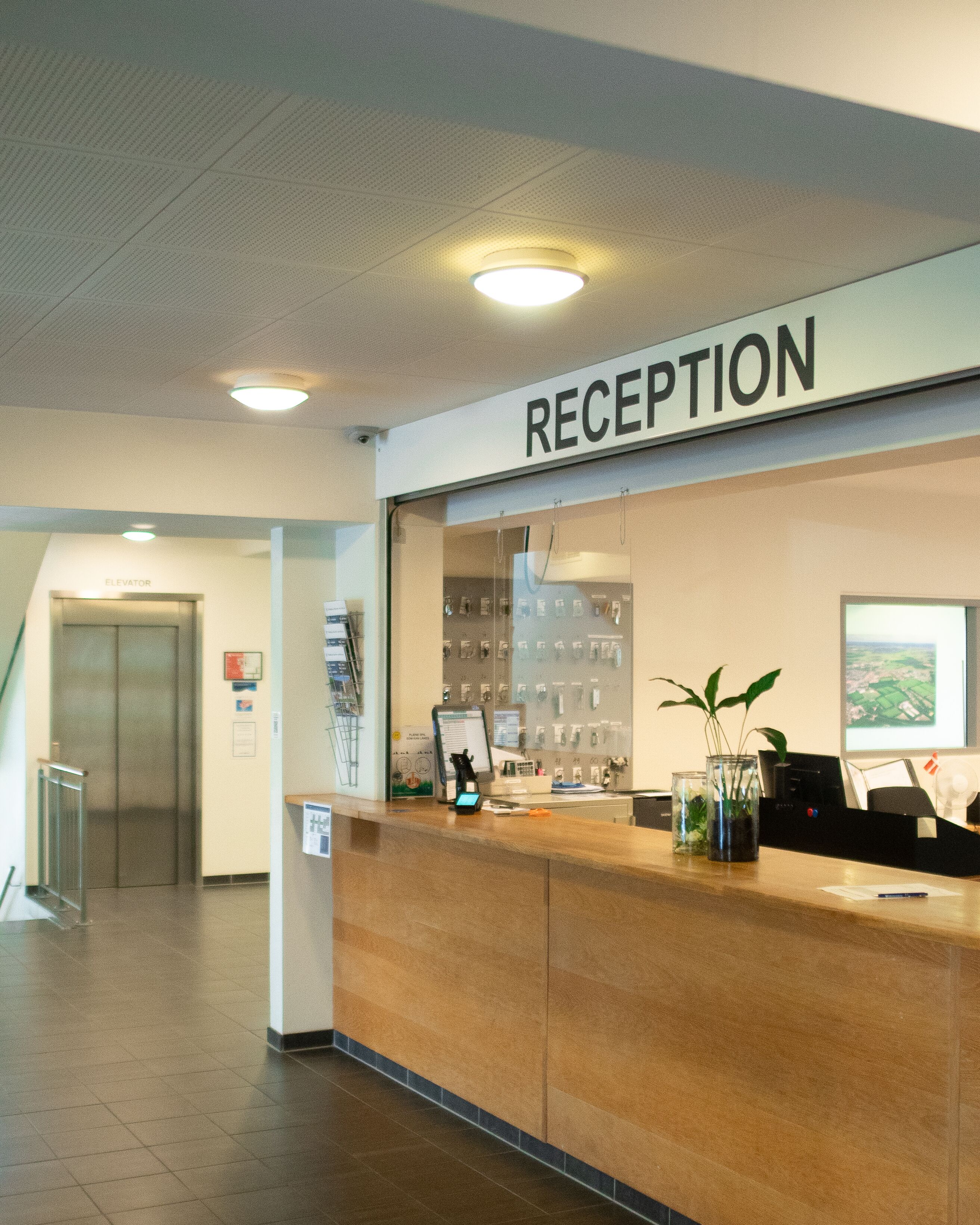A reception area with a reception desk, a sign above it, and a wall-mounted display of items.