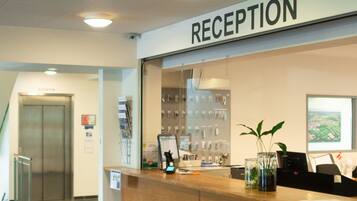 A reception area with a reception desk, a sign above it, and a wall-mounted display of items.