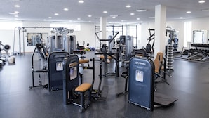 A gym with various exercise machines, mirrors, and a clean, spacious layout.