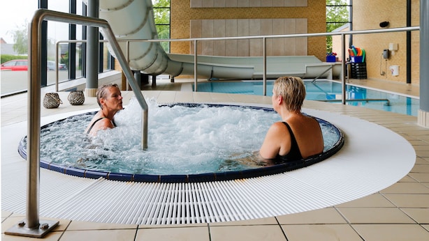 A hot tub with a slide, indoor pool, and a view of the outside.