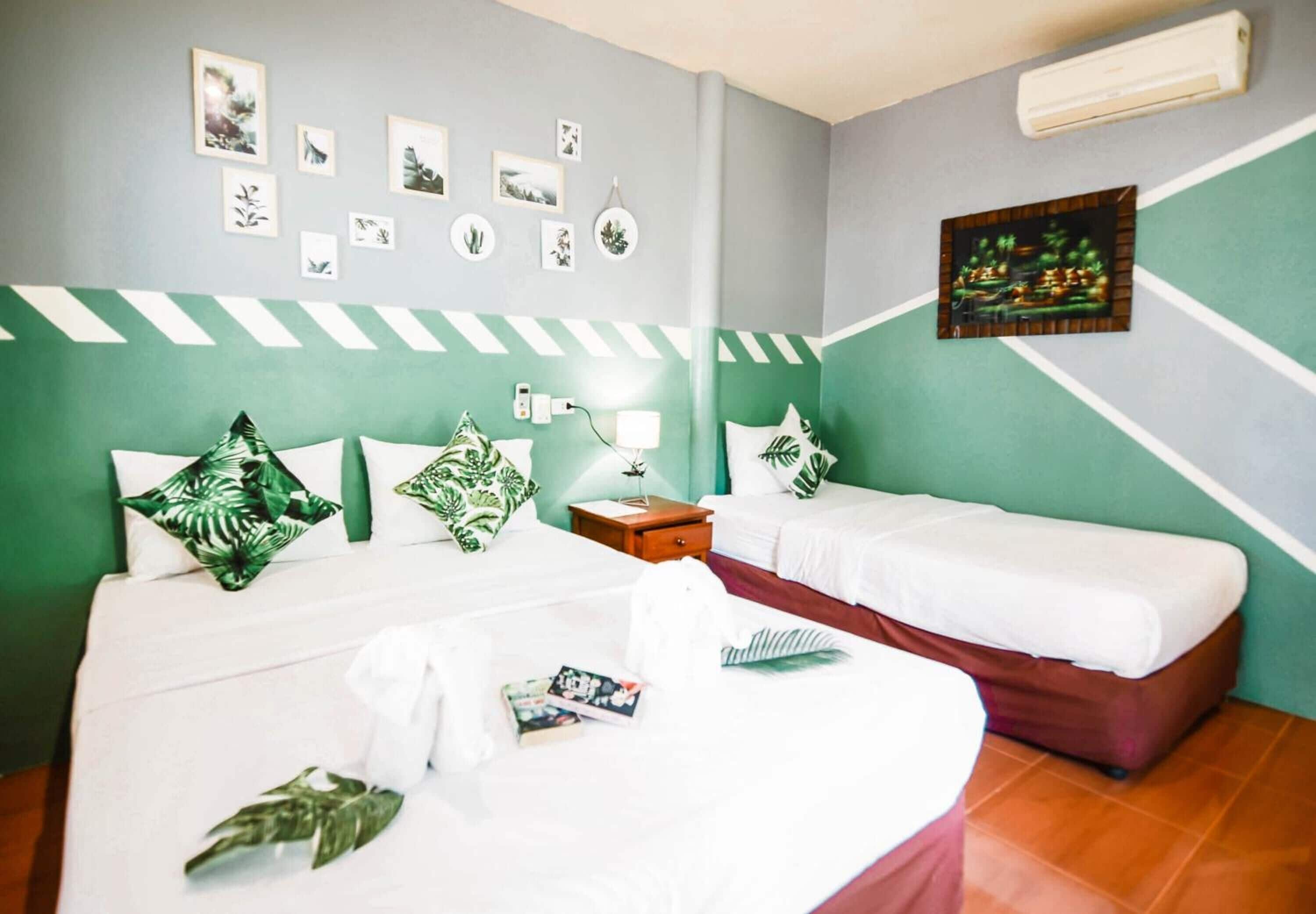 A hotel room with two beds, a nightstand, a lamp, and a wall decorated with framed pictures.
