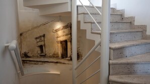 Una escalera con barandilla que conduce a una habitación con un mural de una fachada de edificio.