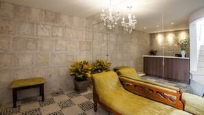 Un vestíbulo moderno con pared de piedra, un banco de madera, un sofá, una araña y una recepción con una planta.