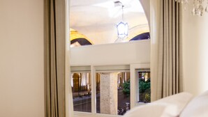 Una habitación de hotel con cama, ventana con cortinas y vista al interior del hotel.