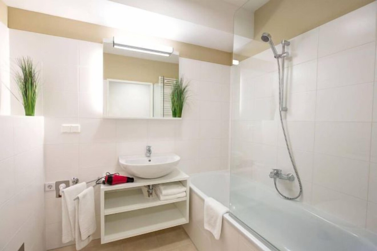 A modern bathroom with a white sink, a glass-enclosed shower, and a mirror above the sink.
