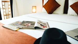 Een net opgemaakt bed met een tijdschrift, kussens en een laptop erop.