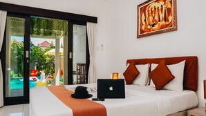 Een hotelkamer met een bed, een laptop, een hoed en een schilderij aan de muur.