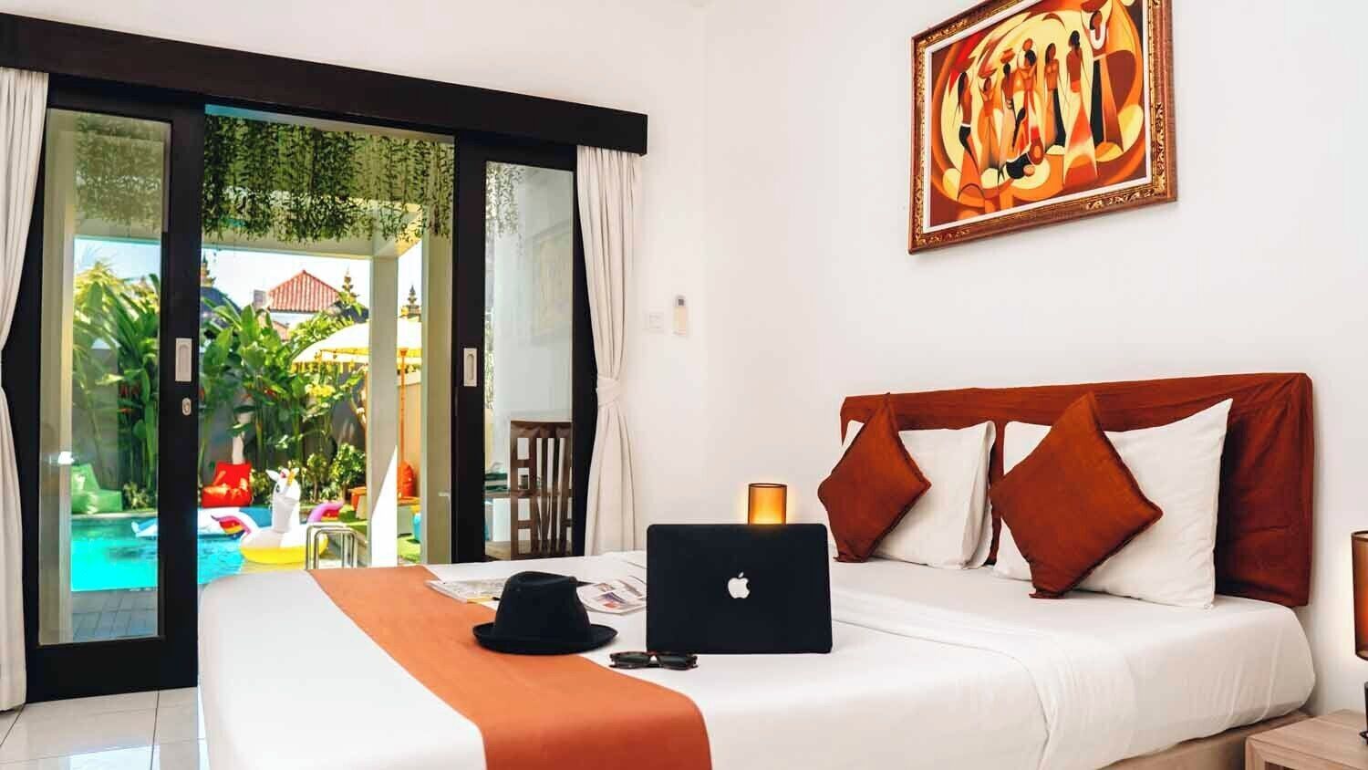 Habitación de hotel con cama, una computadora portátil y vistas a una piscina y zona exterior.